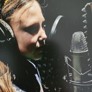Kind singt im Tonstudio mit Kopfhörern und professionellem Mikrofon